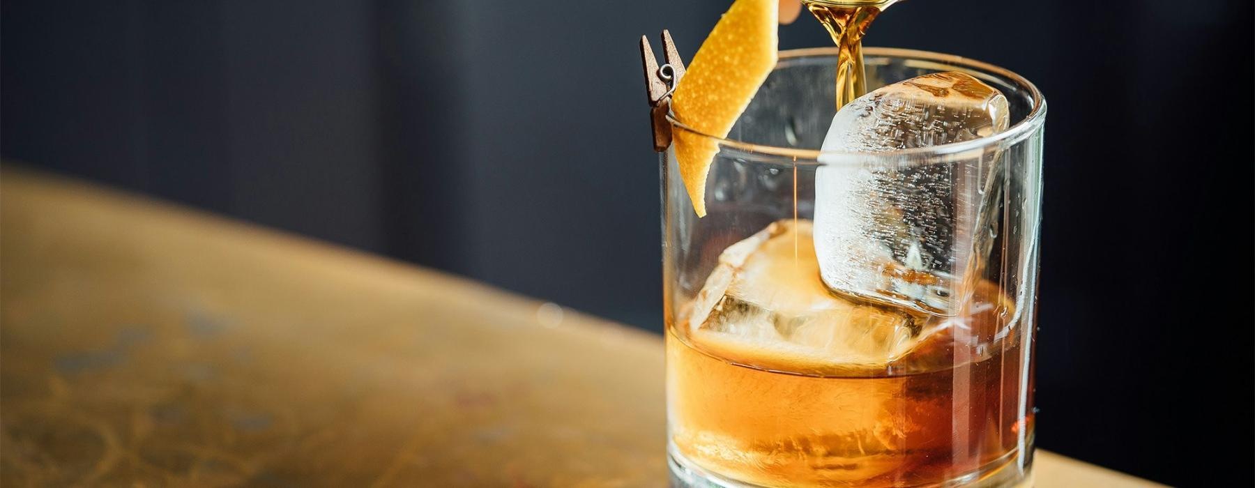 a glass of liquid being poured into a glass with ice